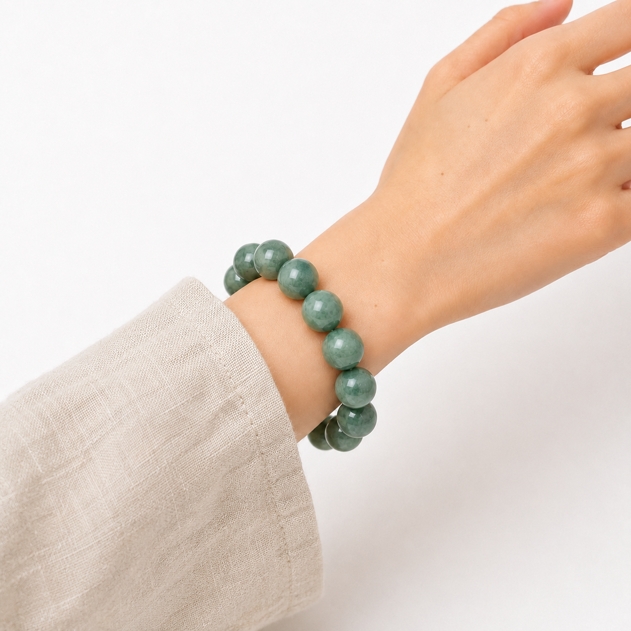 Natural jade bead bracelet worn on the wrist with a light linen sleeve