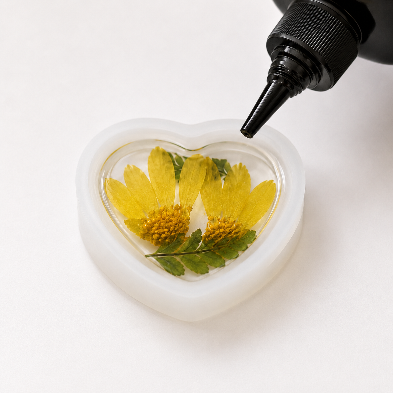 Real flowers being arranged and preserved in clear resin during the jewellery-making process