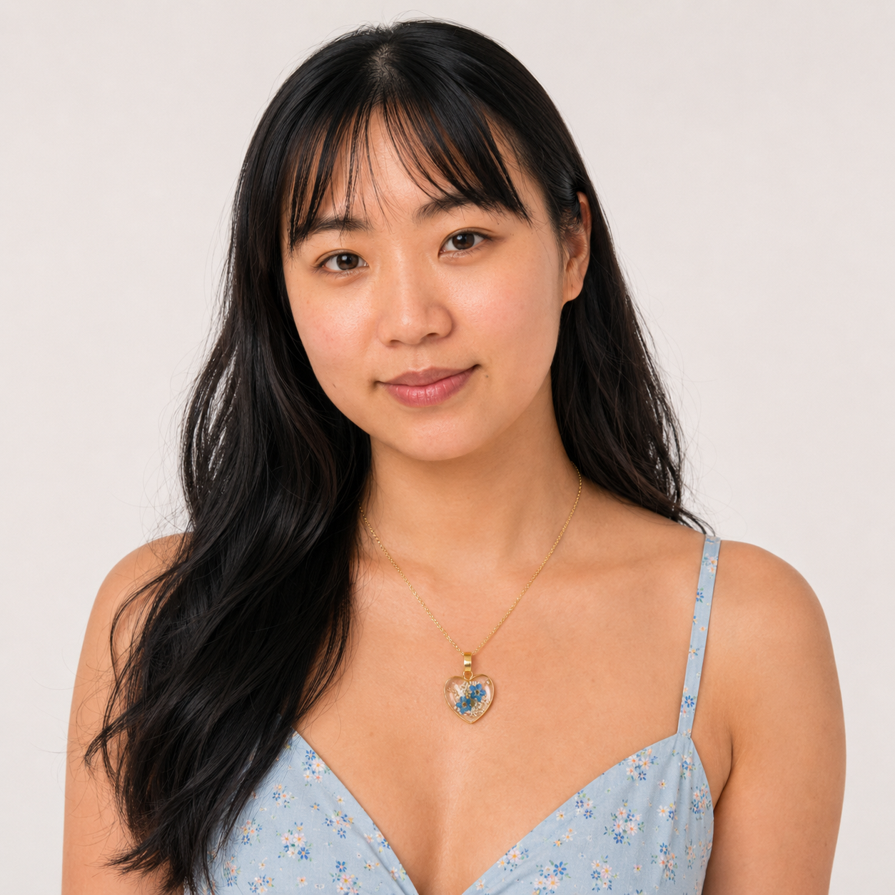 Model wearing a gold Forget-Me-Not heart necklace
